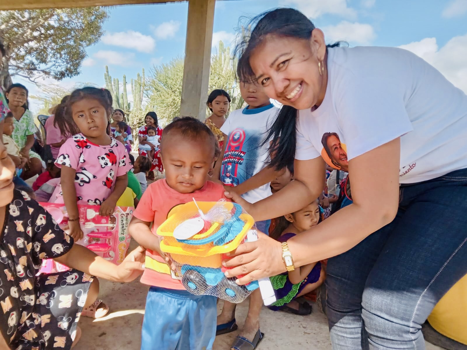 Un niño recibe un juguete acompañado por una representante de la Fundación